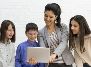 teacher-and-kids-looking-on-tablet-computer-during-Z93CVLY.jpg